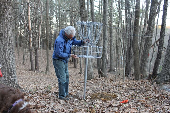 Volunteer installing a disc golf basket in the woods